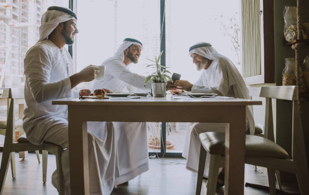 Three business men having a tea in Dubai wearing traditional emirati clothes Three business men having a tea in Dubai wearing traditional emirati clothes old arab man stock pictures, royalty-free photos & images