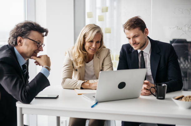 Three business partners working on a laptop stock photo