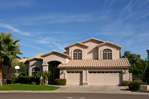 Two story home with three car garage in southwestern neighborhood of Scottsdale, AZ has tiled roof, palm trees, is new, 