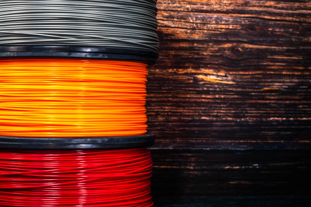 Three coils of filament for 3d printing. Bright thermoplastic of orange, red and grey colors Three coils of filament for 3d printing. Bright thermoplastic of orange, red and grey colors. light bulb filament stock pictures, royalty-free photos & images
