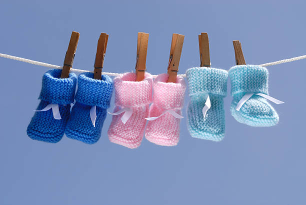 three colorful baby booties hanging on a clothes line stock photo
