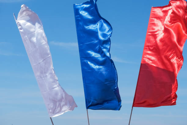 Three colorful flags on flagpoles against blue sky with perspective, corporate flag ,symbol, copy space.Silky fabric in front of bright sky.brightl fabric waving on wind. Promotional and advertisement object Three colorful flags on flagpoles against blue sky with perspective, corporate flag ,symbol, copy space. Advertising flag stock pictures, royalty-free photos & images