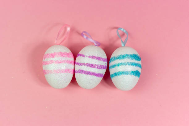 Three Easter eggs of different colors on a pink background. Abstract Easter background. A copy of the space stock photo