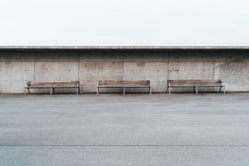 Three Empty Street Outdoor Benches With A Concrete Wall Behind