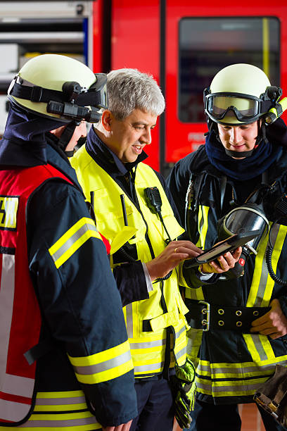 Three fireman discussing with on another on tablet-computer stock photo