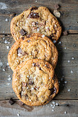 istock Three freshly baked chocolate chip cookies on a wooden background 1243636779
