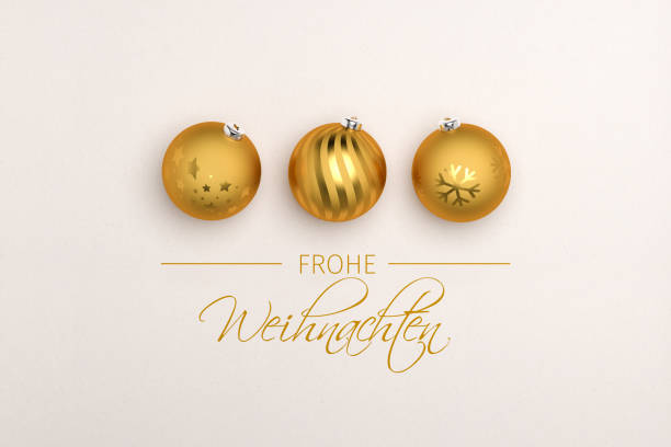 три золотые рождественские безделушки на бумажном фоне. немецкое послание "frohe weihnachten" (счастливого рождества) ниже. - weihnachten стоковые фото и изображения