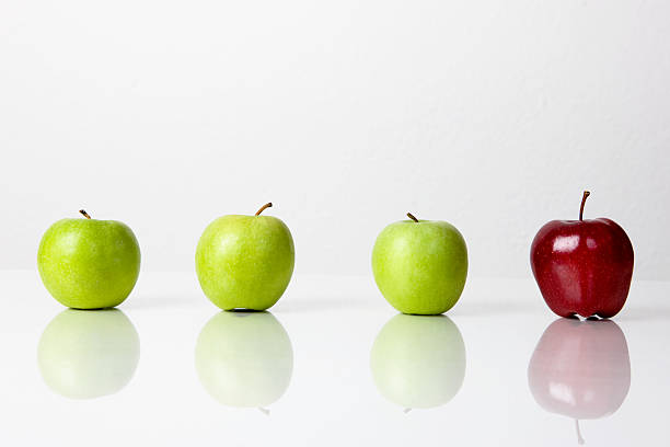 Three green apples and one red on white stock photo