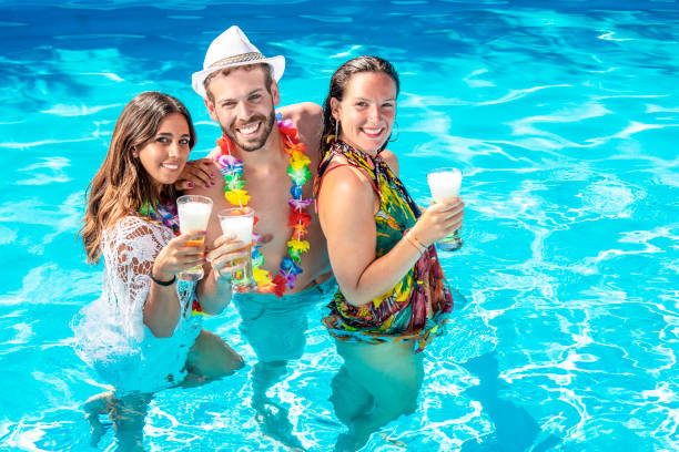 three guys drink beer in the pool at a party stock photo