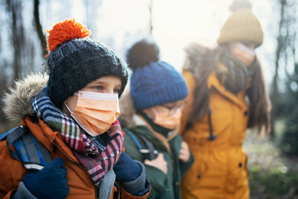 tres niños con máscaras antivirus van a la escuela - resfriado y gripe fotografías e imágenes de stock