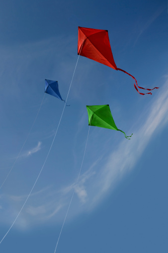 Three kites flying over a fair sky.