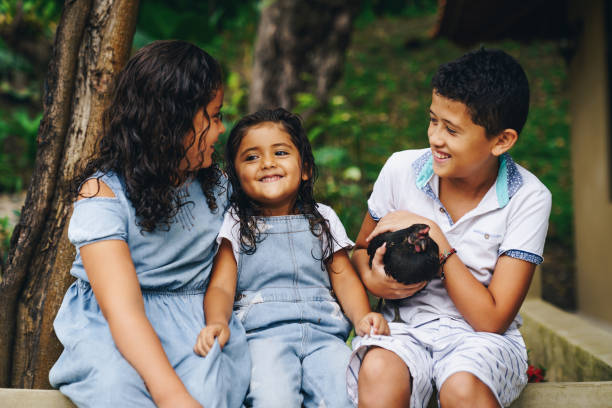 Three Latin children smiling at each other in countryside stock photo