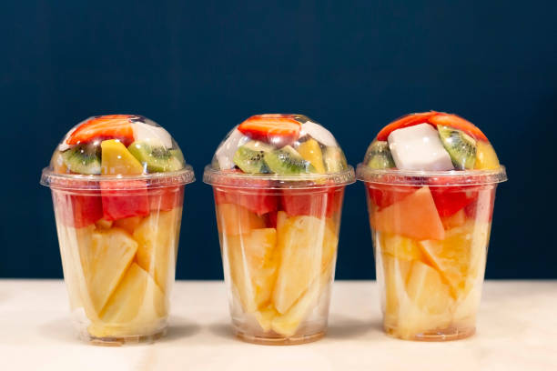 Three mixed fruit vitamin salad in the plastic glass ready to takeaway. Kiwi, pineapple, watermelon, coconut, strawberry, mango in plastic container. Copy space. stock photo