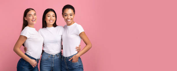 Three Mixed Girls Hugging Posing Over Pink Studio Background, Panorama Three Mixed Girls Hugging Posing Smiling To Camera Over Pink Studio Background. Panorama With Copy Space chinese girl hairstyle stock pictures, royalty-free photos & images