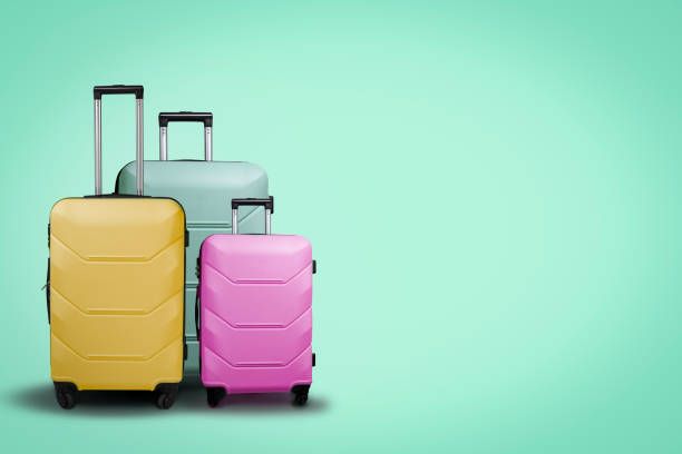 trois valises en plastique multicolores sur roues sur fond vert. concept de voyage, vacances, visite de membres de la famille. - bagage photos et images de collection