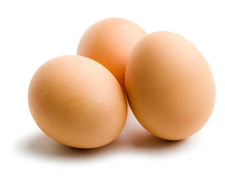 Three brown, organic, fresh, raw eggs, a small group clustered next to each other. Chicken eggs are a dairy grocery, diet staple, and nutritious animal protein source. The brown shells suggest pure, wholesome, natural, farm-raised, free-range food. Cut out and isolated on white background with soft shadows for added  dimension.