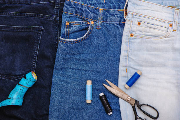 drei jeans mit schere, fäden und schneidermeter. - upcycling stock-fotos und bilder