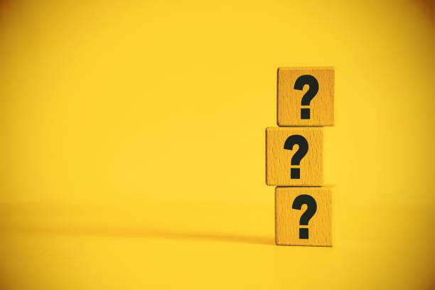 Three question marks in front of yellow background stock photo