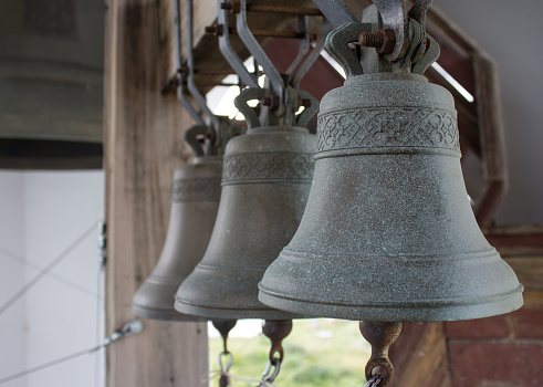 Three small bells arranged in a row on the bell tower of the church