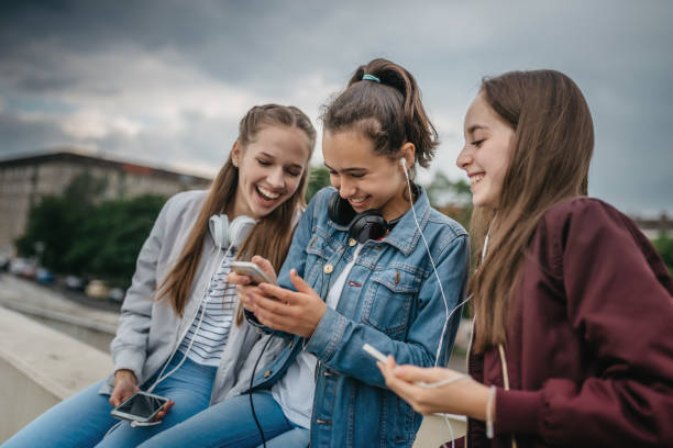 three teenage girls with smartphones outdoors stock photo