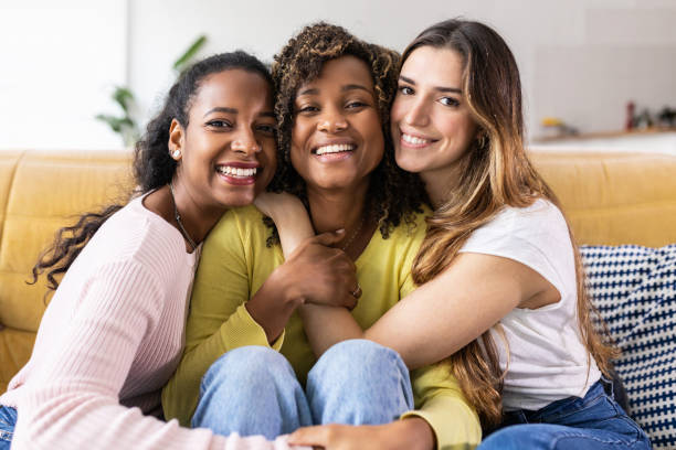 Three united beautiful smiling women sitting together on couch stock photo