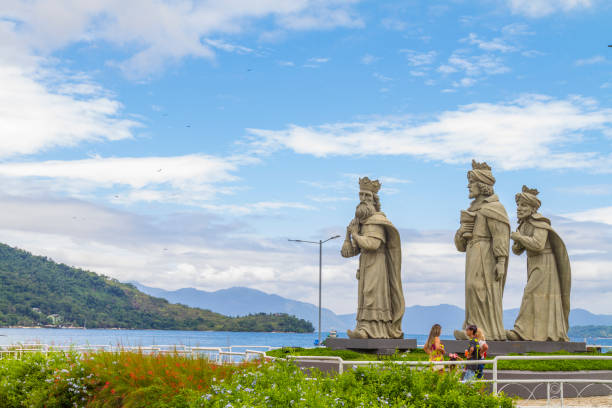 March 5, 2020 - Angra dos Reis, Rio de Janeiro, Brazil: National and international tourists enjoying their vacations and taking a break to take some pictures with Three wise men sculptures in Angra dos Reis, Rio de Janeiro, Brazil. On back, Ilha Grande landscape in a hot summer blue day.