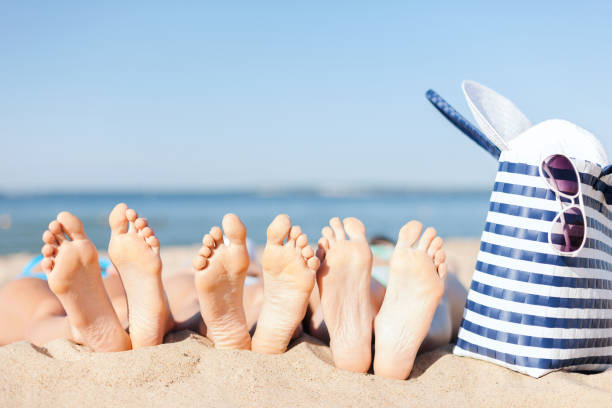 drie vrouwen liggend op het strand - voeten in het zand stockfoto's en -beelden