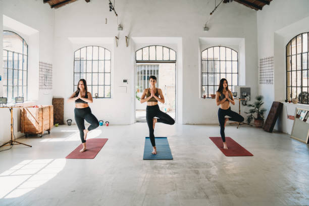 Three young adult women are practicing yoga in a modern loft stock photo