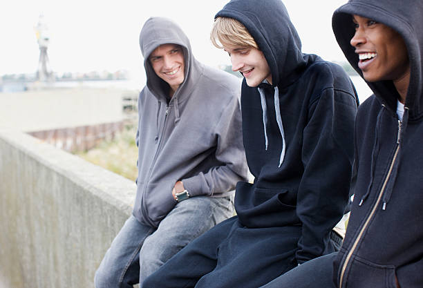 Three young men in hoodies sitting on wall  gang stock pictures, royalty-free photos & images