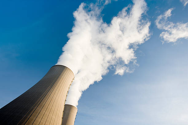 Tilt Shot of Two Steaming Cooling Towers with blue sky stock photo