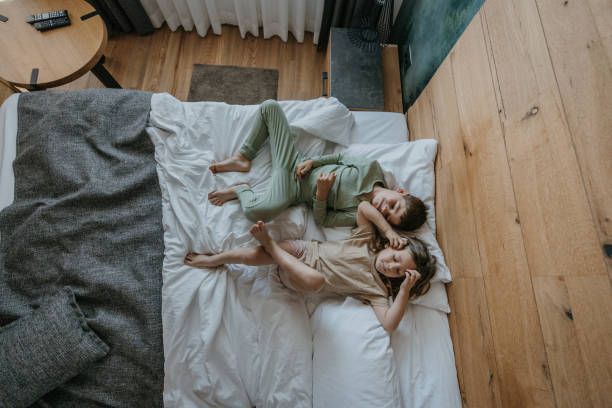 Time for afternoon nap High angle view of little brother and sister sleeping on bed in bedroom during the day lying flat posotion stock pictures, royalty-free photos & images