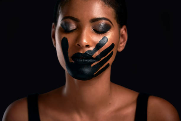 Time to break the silence Studio shot of a young woman with a hand painted on her mouth posing against a black background me too social movement stock pictures, royalty-free photos & images