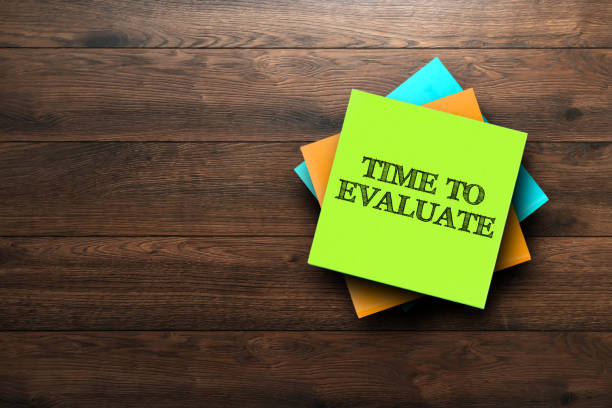Time To Evaluate, the phrase is written on multi-colored stickers, on a brown wooden background. Business concept, strategy, plan, planning. stock photo