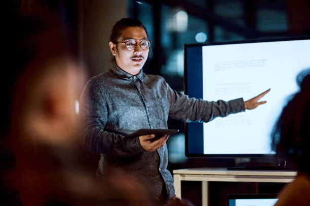 Time to get growing Shot of a young businessman delivering a presentation during a late night meeting at work presentation stock pictures, royalty-free photos & images