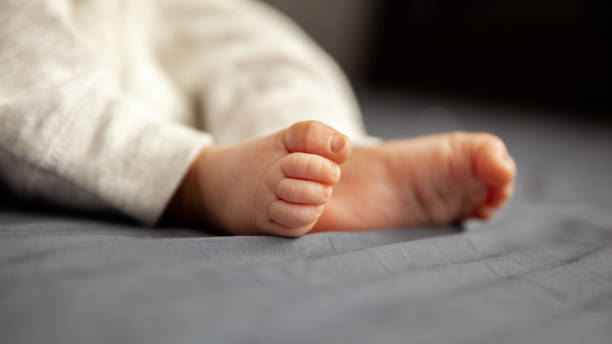 Tiny legs of newborn baby lying on the bed in a selective focus stock photo
