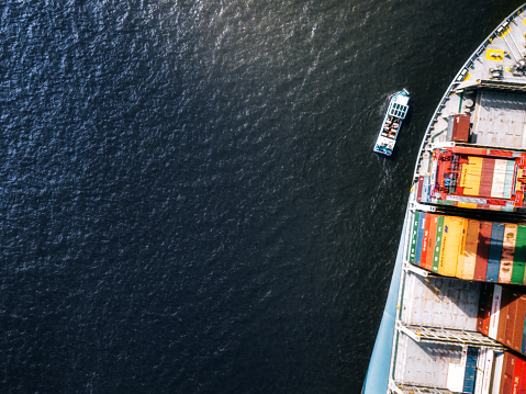 high angle view on huge Cargo container ship beside tiny ship passing beside