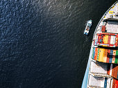 istock tiny ship beside huge container freight ship 1319049224