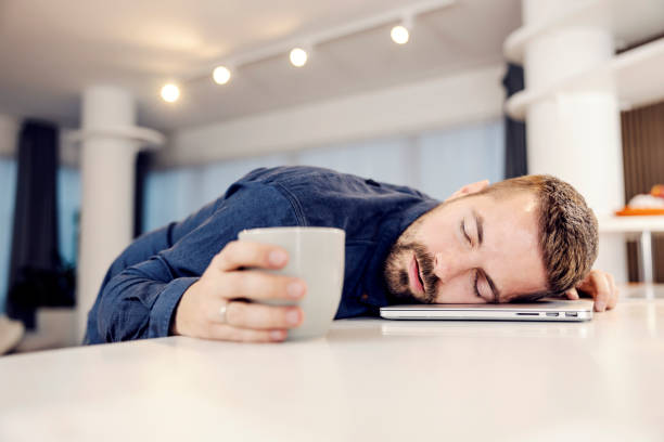 A tired entrepreneur tired of online work sleeping on the laptop at his home. stock photo