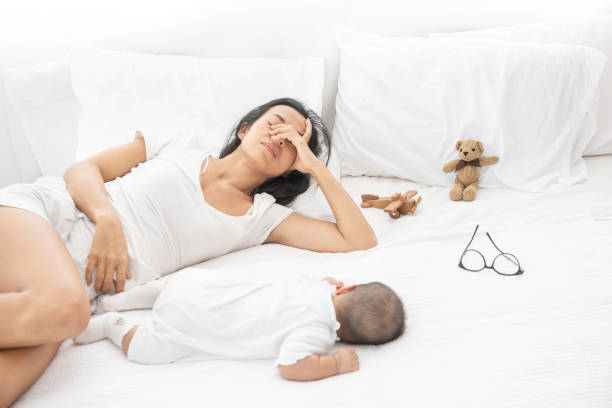 Tired Exhausted Mother Sleeping Sleep With Baby On White Bed stock photo