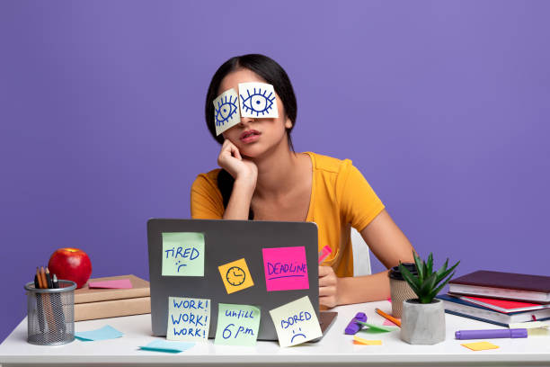 Tired indian woman sitting at desk with sticky notes A Lot Of Work Concept. Portrait of tired female freelancer sleeping at workplace with stickers on eyes, sitting at table over purple studio background. Distracted woman at home office eye stick stock pictures, royalty-free photos & images