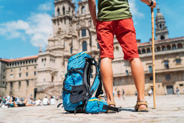 Tired Legs Close up photo of Young backpacker man pilgrim standing on the Obradeiro square (plaza) - the main square in Santiago de Compostela as a end of his Camino de Santiago pilgrimage.  pilgrims monument stock pictures, royalty-free photos & images