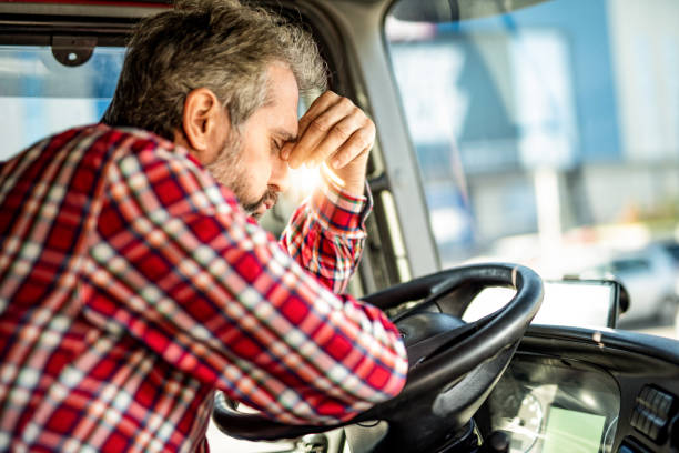 vermoeide rijpe vrachtwagenchauffeur die in verkeer wacht en over baanproblemen overweegt. - moe stockfoto's en -beelden