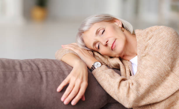 trött mogen kvinna som har tupplur på soffa - nap middle age woman bildbanksfoton och bilder
