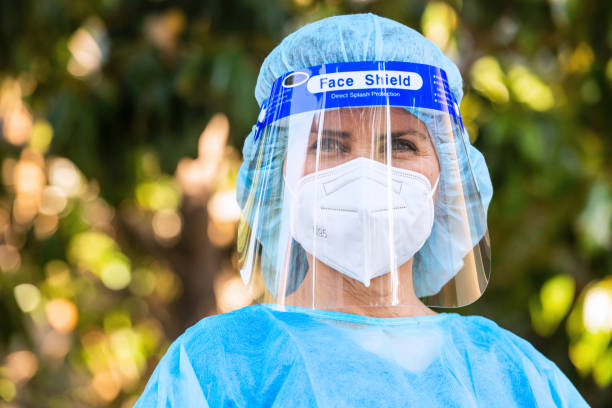Tired, overworked, exhausted health care worker posing outside the hospital while taking a break Tired, overworked, exhausted health care worker posing outside the hospital while taking a break looking at the camera n95 mask stock pictures, royalty-free photos & images