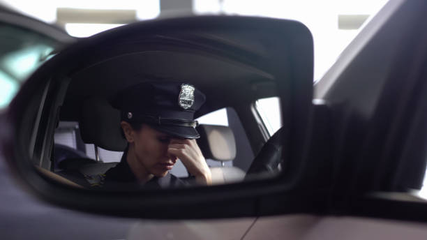 Tired police woman feeling headache, sitting in patrol car, stressed lifestyle stock photo