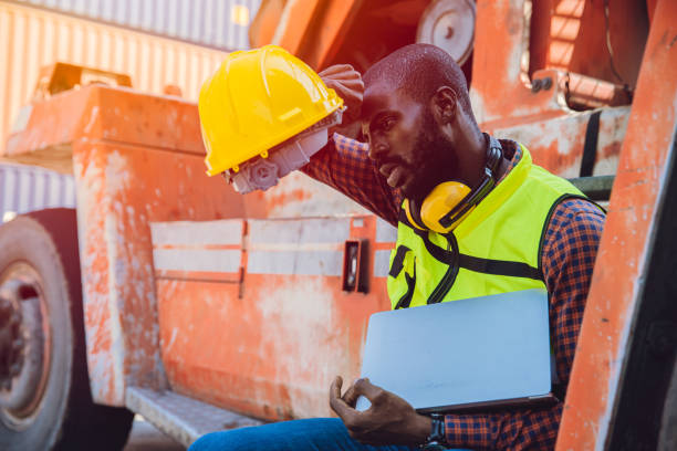Tired stress worker sweat from hot weather in summer working in port goods cargo shipping logistic ground, Black African race people. stock photo