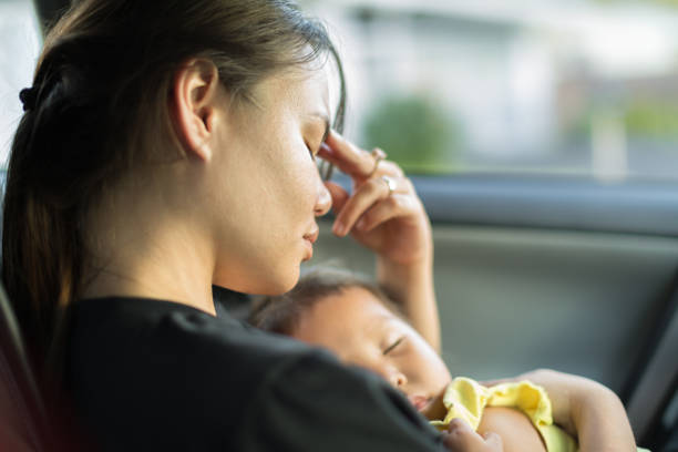 Tired stressed mother holding her baby. A unhappy exhausted mom trying to take a nap with her baby in the car. struggle stock pictures, royalty-free photos & images