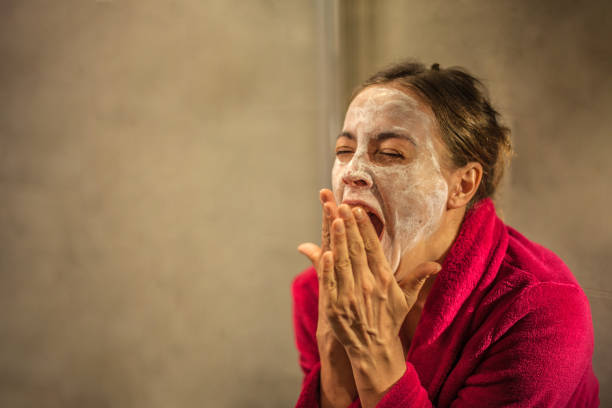 Tired Woman with Beauty Mask on Face During the Evening Routine in the Bathroom stock photo