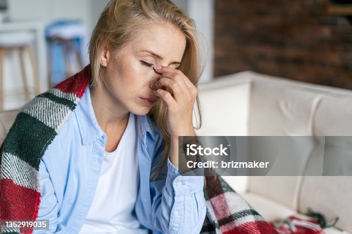 istock Tired woman with closed eyes touching nose bridge 1352919035