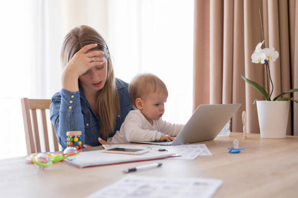moe werkende moeder met kind in haar schoot uitgeput gevoel - geldstress stockfoto's en -beelden